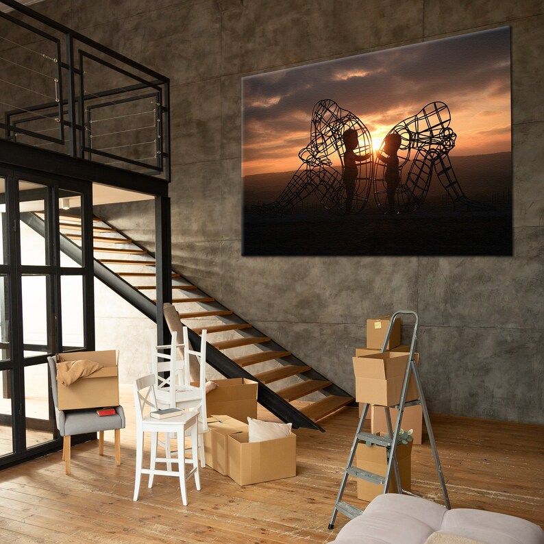 May include: A large canvas print of a silhouette of two children standing inside a metal sculpture against a sunset sky.