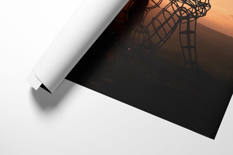 May include: A large metal sculpture of a person sitting with their head down, silhouetted against a sunset.