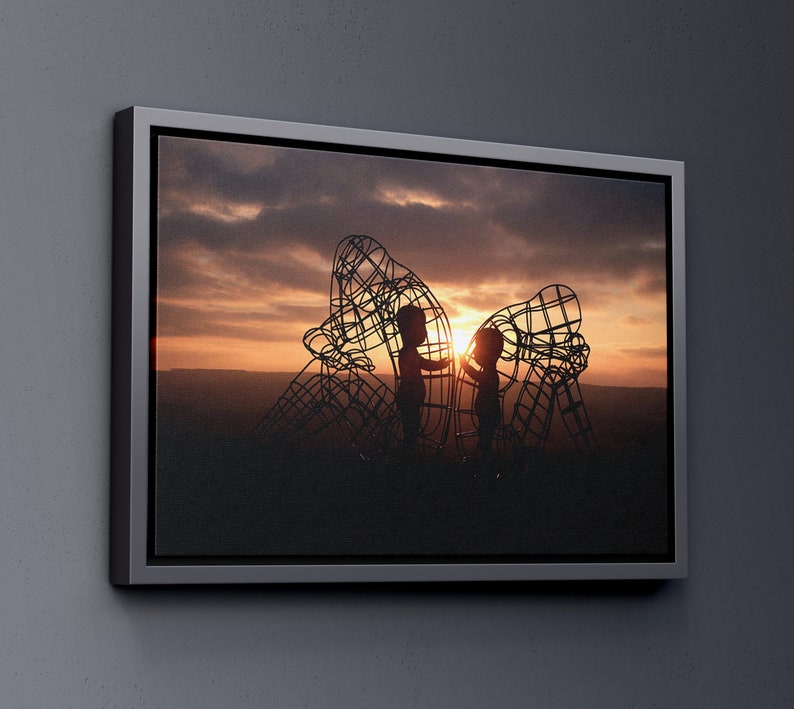 May include: Silhouette of two children standing inside a large metal sculpture against a sunset sky.