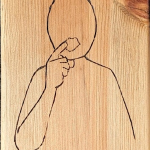 May include: Three hand-drawn figures on a wooden surface, each with a different hand gesture. The figures are simple outlines with circles for heads.