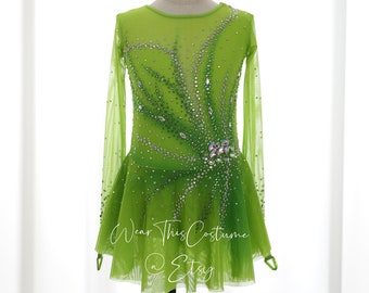 May include: A lime green figure skating dress with long sleeves and a sparkly design. The dress has a fitted bodice and a flared skirt. The dress is decorated with rhinestones and crystals. "Wear This Costume @ Etsy" is printed on the skirt.