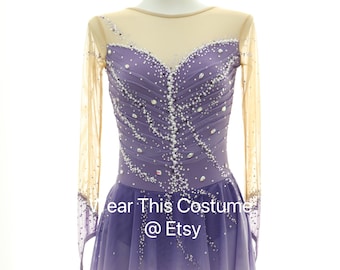 Può includere: Un abito da pattinaggio artistico viola con maniche lunghe e una gonna di tulle. L'abito è decorato con strass e perle. Il testo "Wear This Costume @ Etsy" è stampato sulla gonna.