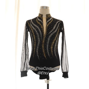 May include: Black figure skating costume with long sleeves and a high neckline. The costume is embellished with gold and silver rhinestones in a wavy pattern. The sleeves are made of sheer mesh.