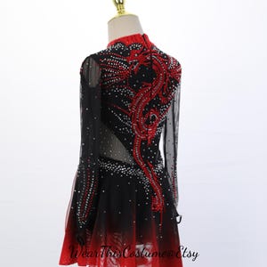 May include: A black and red long-sleeved dress featuring a high neckline and a dragon motif embellished with crystals. The bodice has sheer side panels, and the skirt transitions from black to red with an asymmetrical hem. Text reads WearThisCostume@Etsy.