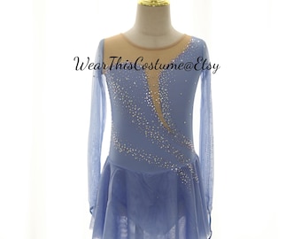 May include: A light blue figure skating dress with long sleeves and a mesh skirt. The dress features a nude mesh neckline and is embellished with rhinestones. The text "Wear This Costume@Etsy" is printed on the dress.