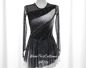 May include: Black and white figure skating dress with long sleeves and a layered skirt. The dress is decorated with rhinestones and has a white underlay. The dress is on a mannequin against a white background. "Wear This Costume @Etsy" is written on the dress.