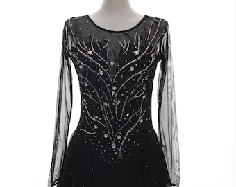 May include: Black figure skating dress with long sheer sleeves and a jewel-encrusted bodice. The dress features a scoop neckline and a flared skirt. The text "WearThisCostume @Etsy" is printed on the skirt.