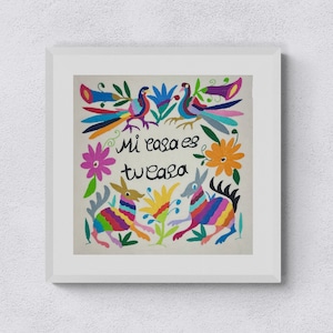 Puede incluir: Una obra de arte bordada colorida con dos animales estilizados, pájaros y flores. El texto "Mi casa es tu casa" está escrito en letras cursivas negras.