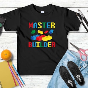 May include: Black t-shirt with the text "MASTER BUILDER" in colorful pixelated letters and a graphic of colorful toy building blocks.