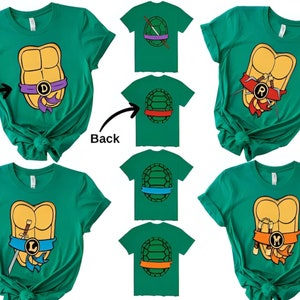 May include: Set of four green t-shirts featuring Teenage Mutant Ninja Turtles characters. Each shirt has a different turtle's shell with their signature weapon and letter. The shirts are shown in front and back views.