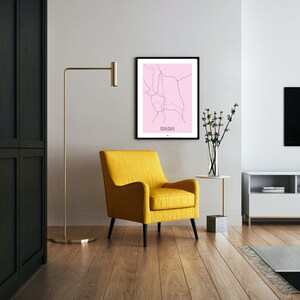 Może przedstawiać: Ż&oacute;łty fotel z czarnymi nogami w salonie z czarną szafą, lampą stojącą, białą ścianą, oprawioną mapą Tuluzy, wazą z r&oacute;żowymi kwiatami i białym centrum rozrywki z czarnym telewizorem.