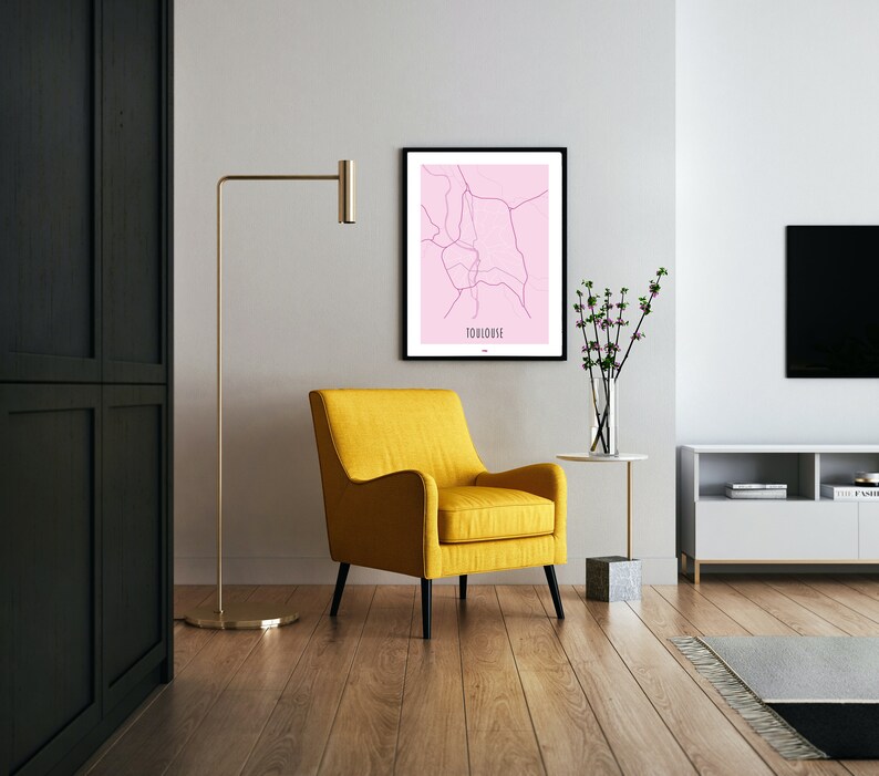 Może przedstawiać: Ż&oacute;łty fotel z czarnymi nogami w salonie z czarną szafą, lampą stojącą, białą ścianą, oprawioną mapą Tuluzy, wazą z r&oacute;żowymi kwiatami i białym centrum rozrywki z czarnym telewizorem.