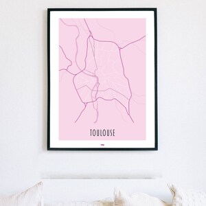 Może przedstawiać: Wydruk w ramie przedstawiający r&oacute;żową mapę Tuluzy we Francji. Mapa jest w czarnej ramie, a nazwa miasta jest wydrukowana na dole mapy czarnym kolorem.