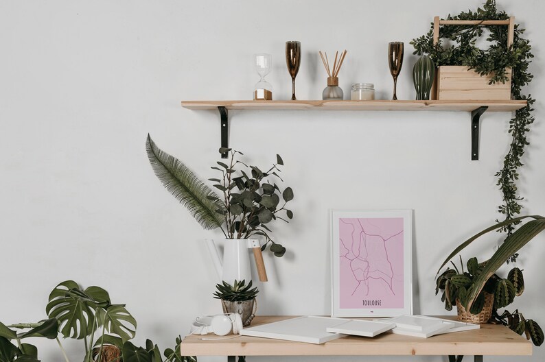 Może przedstawiać: Drewniana p&oacute;łka na tle białej ściany, ozdobiona roślinami, wydrukiem mapy i r&oacute;żnymi elementami dekoracyjnymi. P&oacute;łka jest zamontowana na białej ścianie.