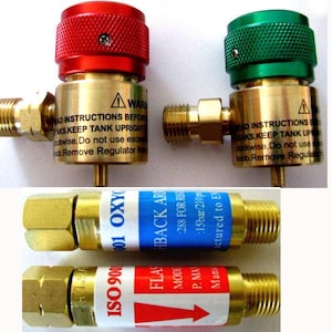 May include: Two brass regulators with red and green caps, and two brass adapters with blue and red labels. The labels on the adapters read "ISO 9001 01 OXY" and "FLASHBACK AR".