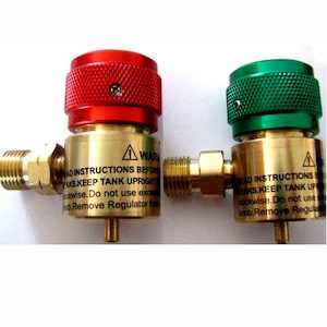 May include: Two brass gas regulators with red and green knobs. The regulators have a warning label that reads "Read instructions before use. Keep tank upright. Turn knob clockwise. Do not use excessive force. Remove regulator from tank before disconnecting hose."