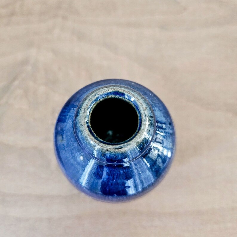 Pu&ograve; includere: Un vaso in ceramica blu scuro con finitura smaltata. Il vaso ha un corpo rotondo e un'ampia apertura.