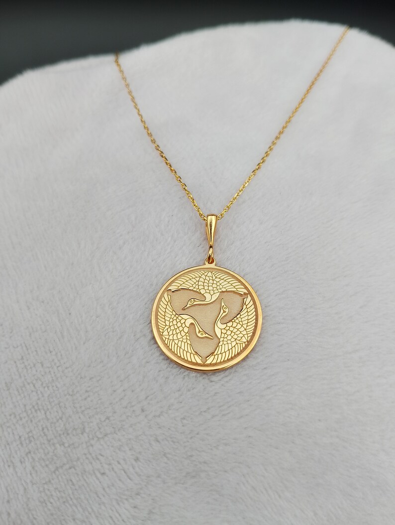 a gold necklace with a bird on it