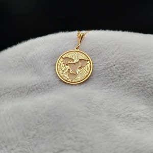 a gold pendant with a bird on it