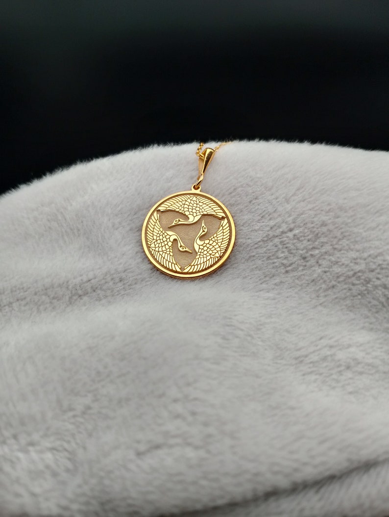 a gold pendant with a bird on it