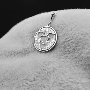 a close up of a person's hand with a pendant on it