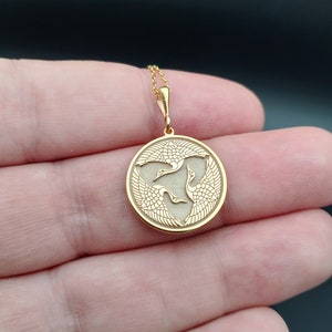 a person holding a gold pendant in their hand