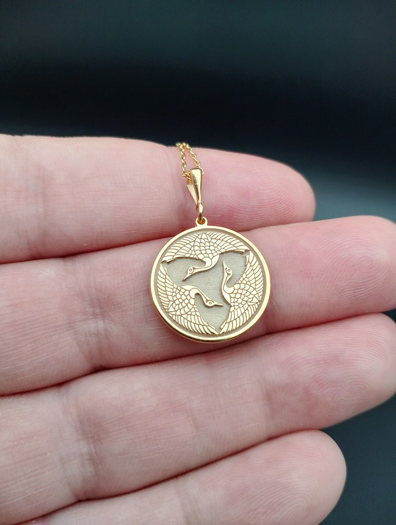 a person holding a gold pendant in their hand