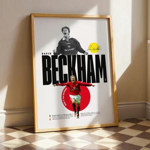 Puede incluir: Póster enmarcado con David Beckham con camiseta de fútbol roja, con los brazos extendidos, sobre un círculo rojo. El póster incluye el nombre "BECKHAM" en letras negras en negrita, con un círculo amarillo y una firma.