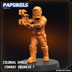 May include: A detailed, orange-toned figurine of a Colonial Space Combat Engineer 7, holding a large weapon. The figure is wearing a futuristic armored suit and helmet. The text "Papsikels" is at the top, with "Colonial Space Combat Engineer 7" and "December 2024 Release" at the bottom.
