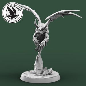 May include: A grayscale figurine of a winged creature with horns, perched atop a stylized base. The figure has a detailed, textured appearance, with outstretched wings and a menacing expression. The base has a circular design. The Falcon Nest logo is in the upper left.