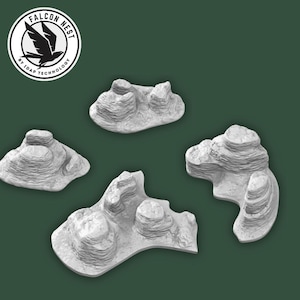 Puede incluir: Cuatro formaciones rocosas grises claras, en capas y de varios tamaños, se muestran sobre un fondo verde oscuro. Las rocas tienen un aspecto texturizado. El logotipo de Falcon Nest está en la esquina superior izquierda.