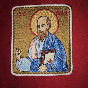 May include: Embroidered patch featuring a gold background with a depiction of Saint Paul holding a book. The patch has a white border and the text "ST PAUL" is embroidered in gold at the top.
