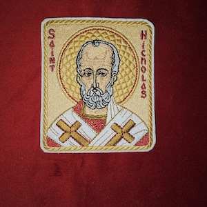 May include: Embroidered patch featuring a depiction of Saint Nicholas, with the words "Saint Nicholas" embroidered on the patch.