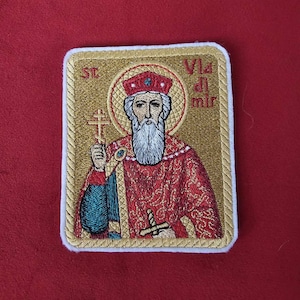 Peut inclure: Patch brodé avec un fond doré et une image rouge et or d'un homme barbu portant une couronne. Le texte "St. Vlad. al. mir." est brodé en or sur le patch.