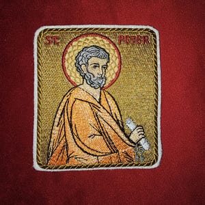 Può includere: Toppa ricamata con sfondo dorato che raffigura San Pietro che tiene un rotolo. La toppa ha un bordo bianco e il testo "ST. PETER" è ricamato in rosso.