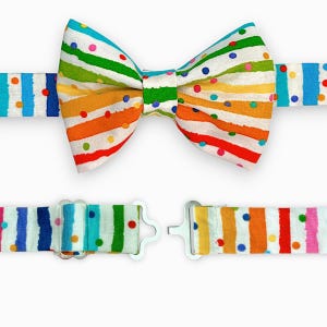 May include: A colorful bow tie with white stripes and multi-colored dots. The bow tie is adjustable with a buckle closure.
