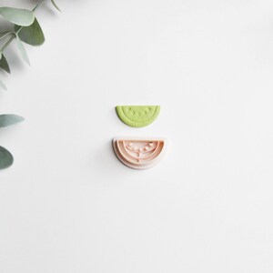 Peut inclure: Deux emportes-pièces en forme de tranches de pastèque. L'emporte-pièce du haut est vert et l'emporte-pièce du bas est rose.