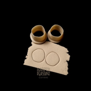 Può includere: Due tagliabiscotti in plastica beige a forma di cerchio, posizionati su una superficie beige con la scritta "Harper Rayne Cutters" stampata su di essa.
