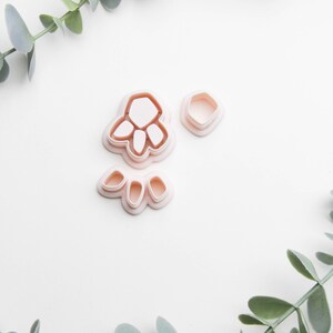 Könnte beinhalten: Ein Set mit drei rosafarbenen Plastik-Ausstechern in Form einer Pfote und zwei kleineren Pfoten.