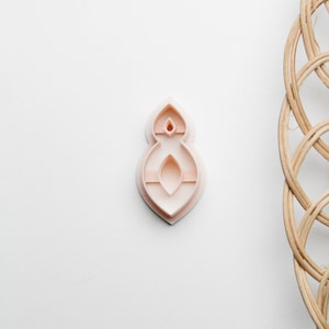 Può includere: Un tagliapasta in plastica rosa a forma di numero otto. Il tagliapasta ha un design decorativo con più strati.