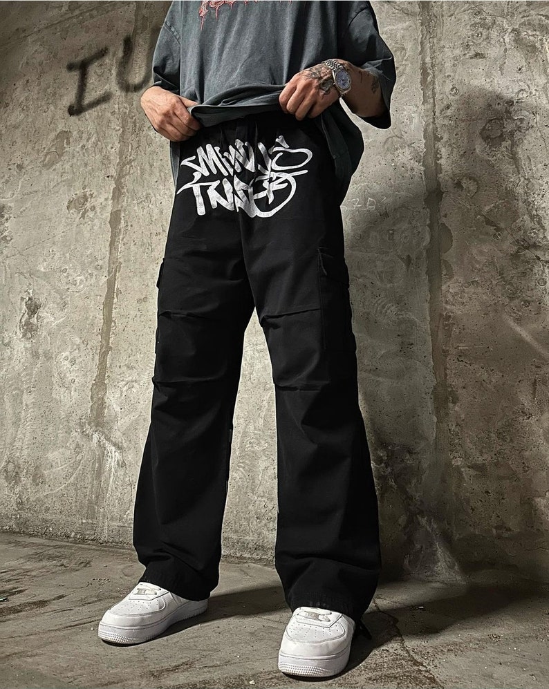 May include: Black cargo pants with a white graphic print that says "SMALL TRIBE" on the front.