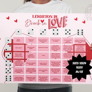 Op de afbeelding: Een roze feestspelposter met de tekst "Leighton is Drunk in Love" en dobbelsteenillustraties. De poster bevat verschillende drinkspelinstructies en maatopties: 18x24, 16x20 en A4/A3.