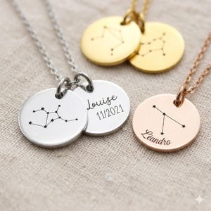 Pode incluir: Uma coleção de colares de constelação personalizados em prata, ouro e ouro rosa. Cada colar apresenta um pingente redondo com um design de constelação e um nome ou data. Os textos "Louise 11/2021" e "Leandro" são visíveis.