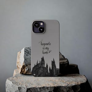 May include: Grey smartphone case with a black and white castle illustration and the text "hogwarts is my home." The case is designed for a mobile phone and has a camera cutout.