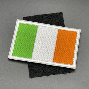 Könnte beinhalten: Ein grüner, weißer und orangefarbener gestickter Aufnäher mit den Farben der irischen Flagge. Der Aufnäher ist an einem schwarzen Klettverschluss befestigt.