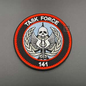 May include: A black and red embroidered patch with a skull and crossbones design. The patch reads "TASK FORCE 141".