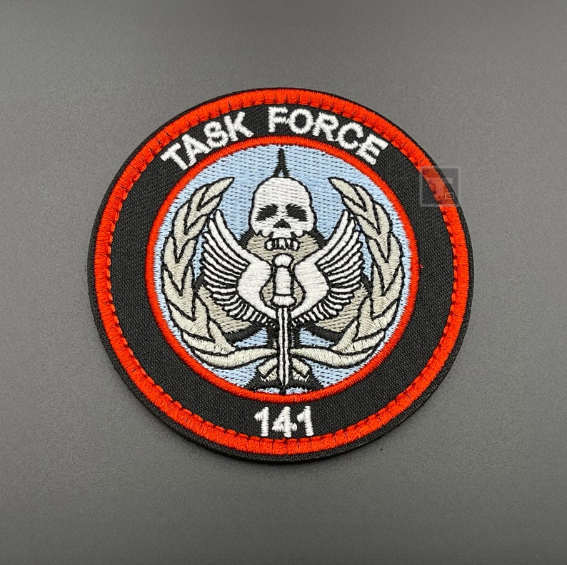 May include: A black and red embroidered patch with a skull and crossbones design. The patch reads "TASK FORCE 141".