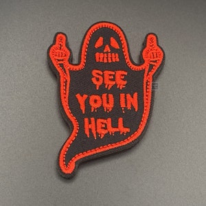 May include: A black and red embroidered patch shaped like a ghost with two middle fingers raised and the text "See you in Hell".