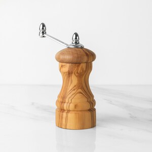 Stylish Olive Wood Grinder, a blend of form and function, comes with a twistable handle for precise seasoning, accompanied by a complimentary wood wax to maintain its finish.