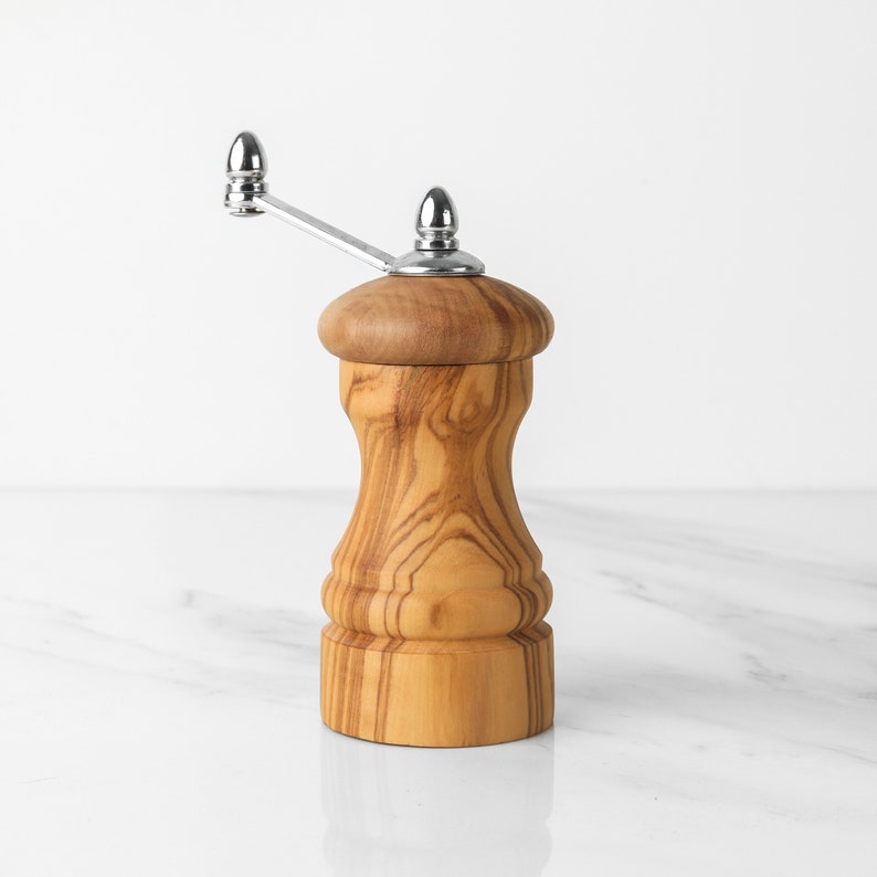 Stylish Olive Wood Grinder, a blend of form and function, comes with a twistable handle for precise seasoning, accompanied by a complimentary wood wax to maintain its finish.